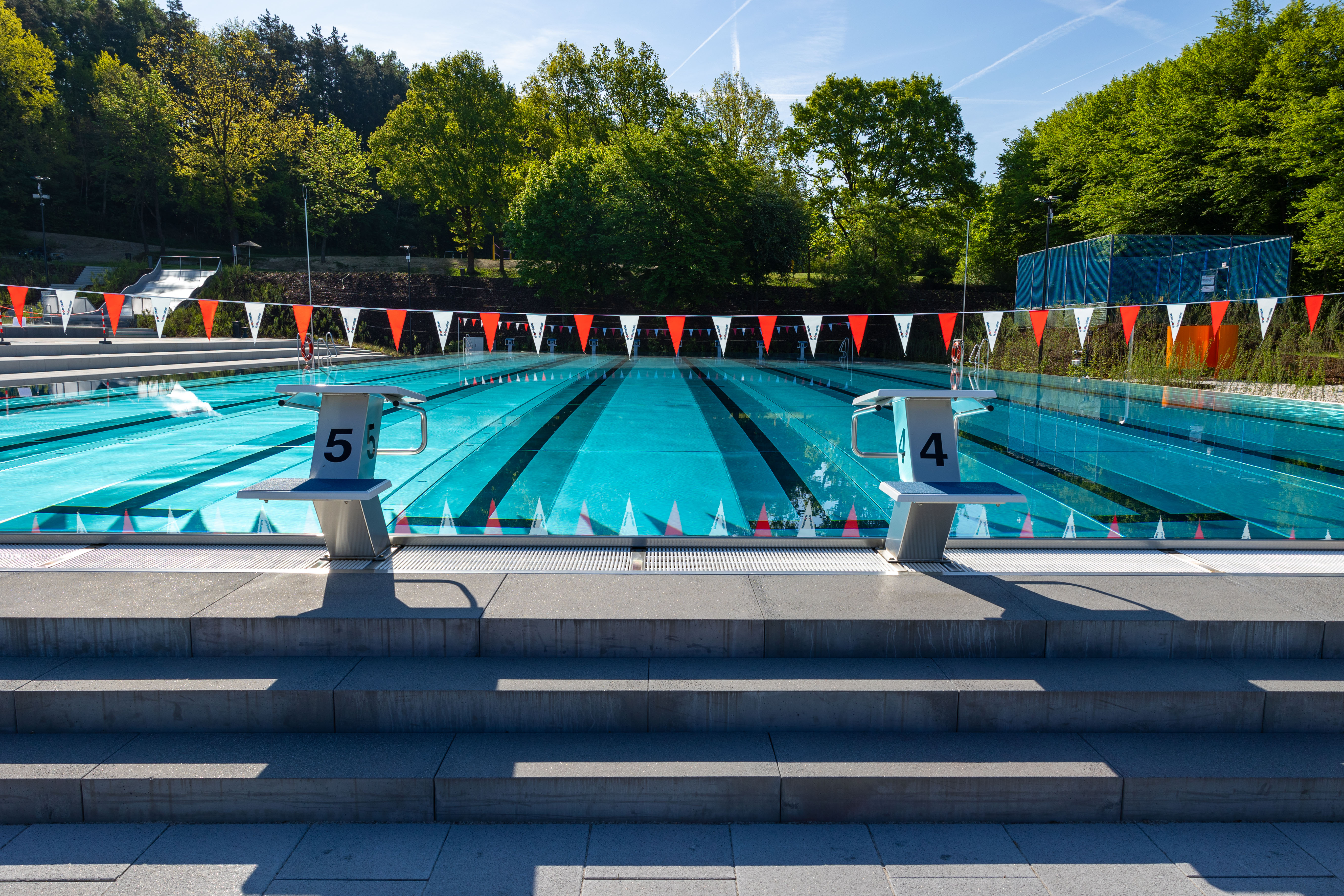 Zwei Startblöcke am Schwimmbecken mit Wasser und Bäumen