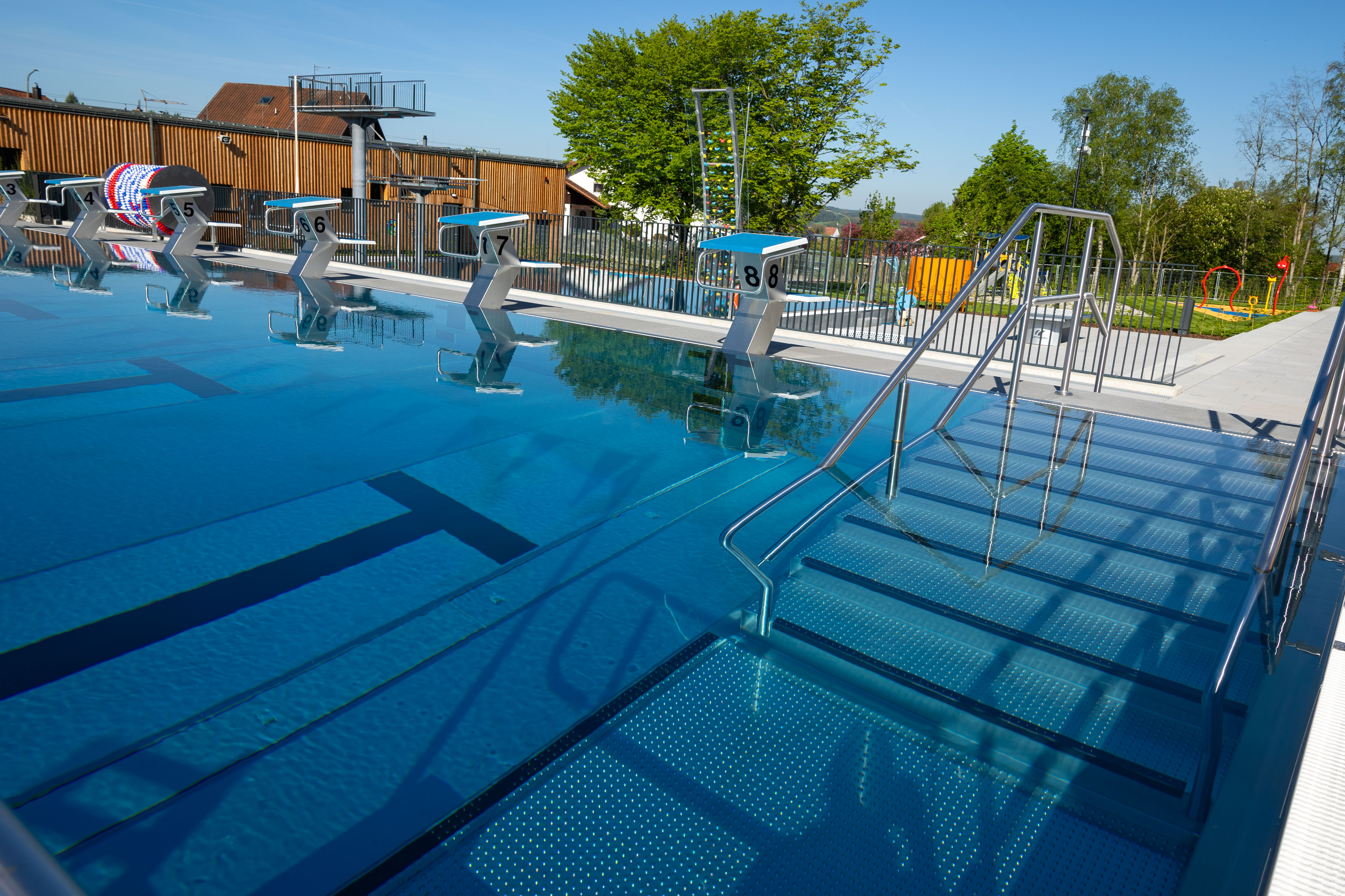 Schwimmbecken mit Startblöcken und Treppe im Freibad