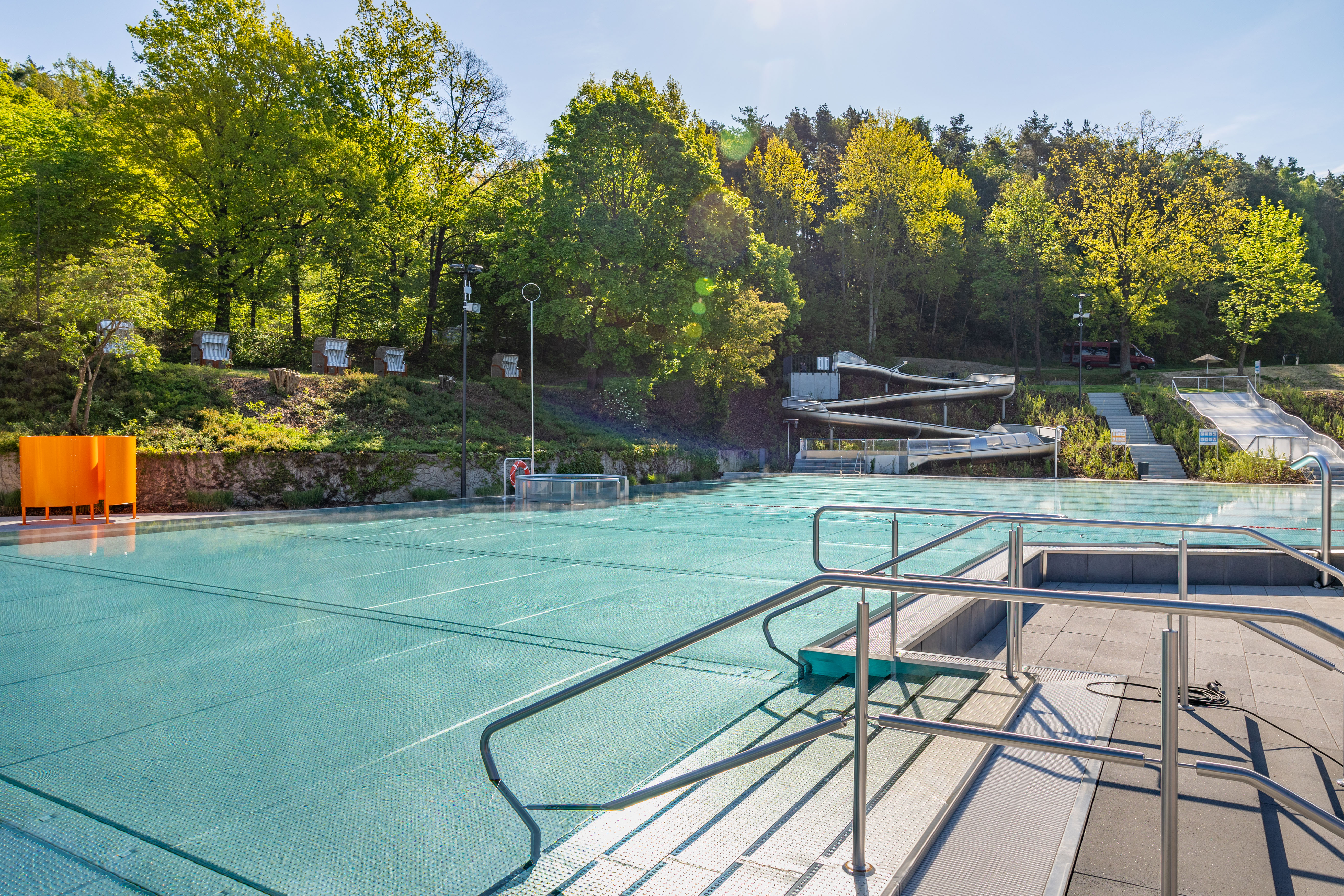Blick auf das Freibad mit Rutschen und Bäumen im Hintergrund.