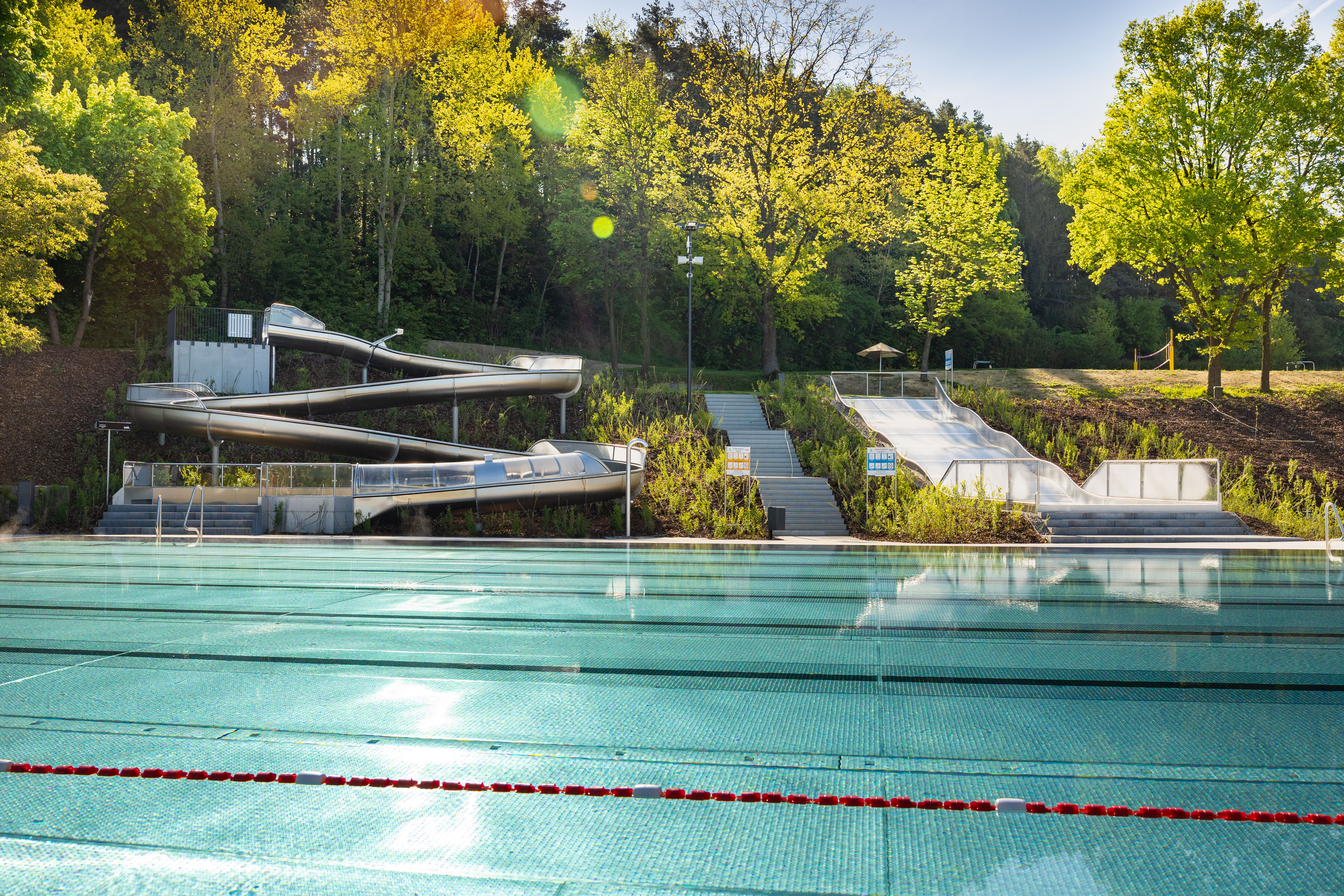 Zwei Wasserrutschen und ein Schwimmbecken im Freibad.