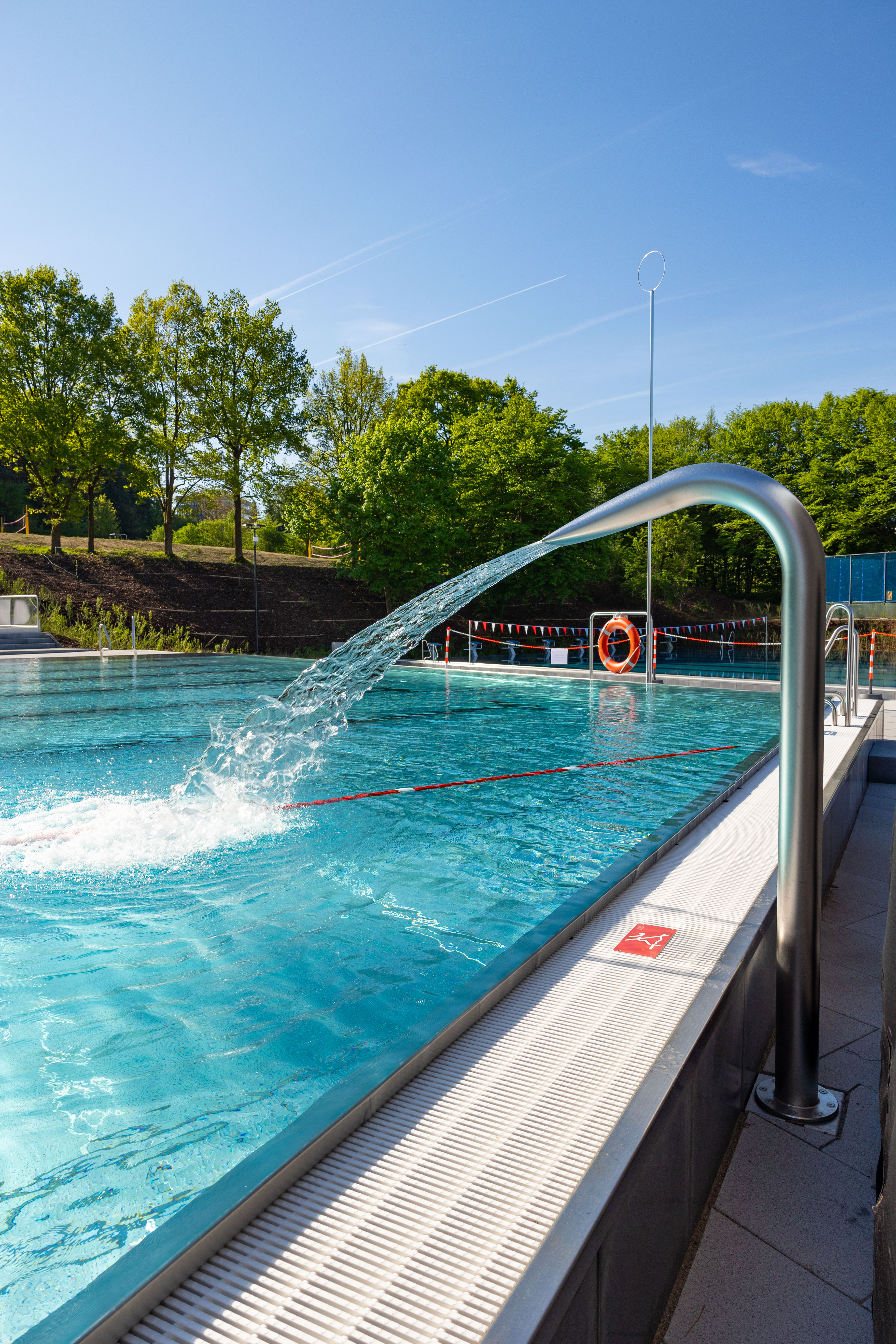 Sprudelndes Wasser aus einem Edelstahlrohr im Freibad