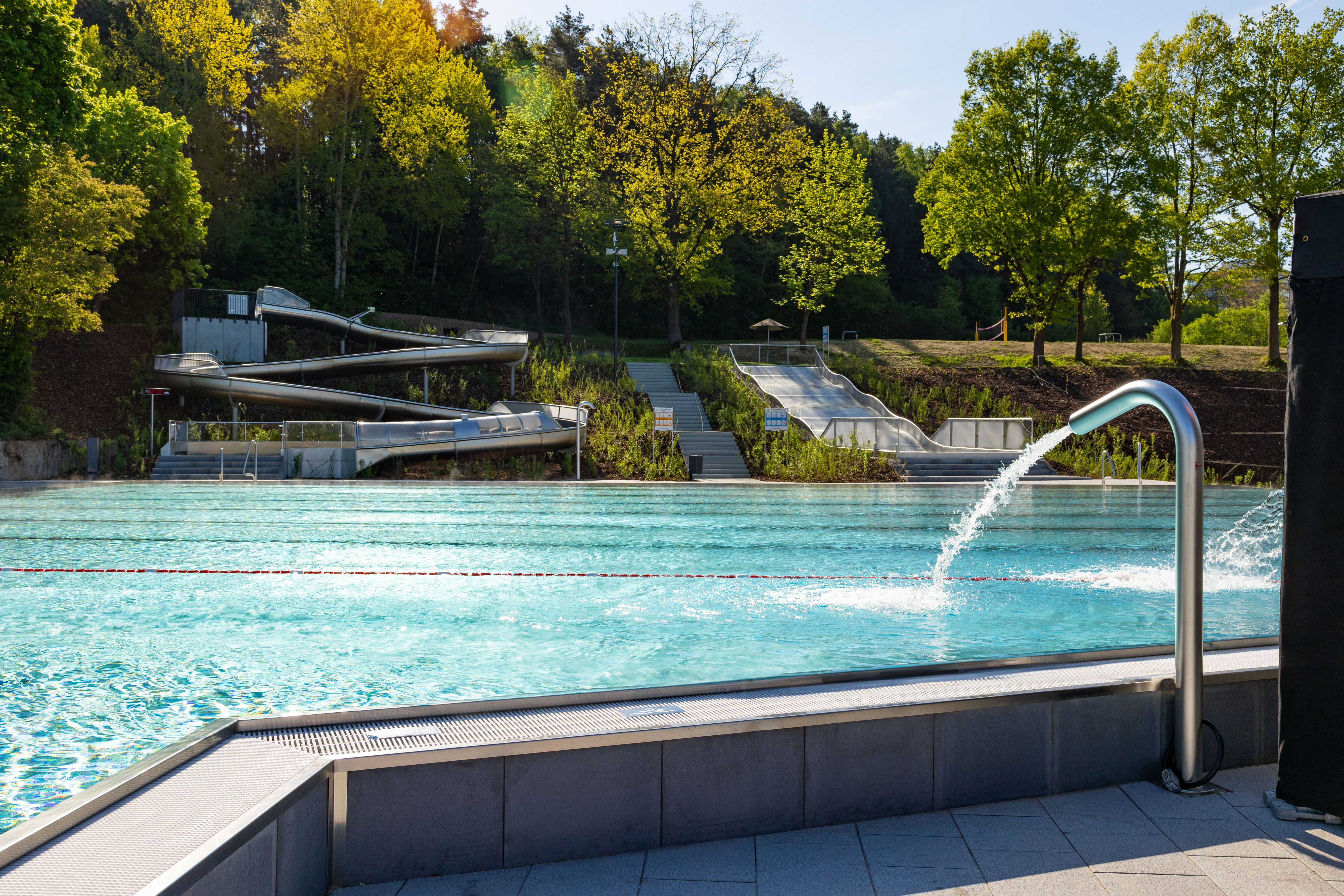 Blick auf das Freibad mit Rutschen und Wasserfontäne.