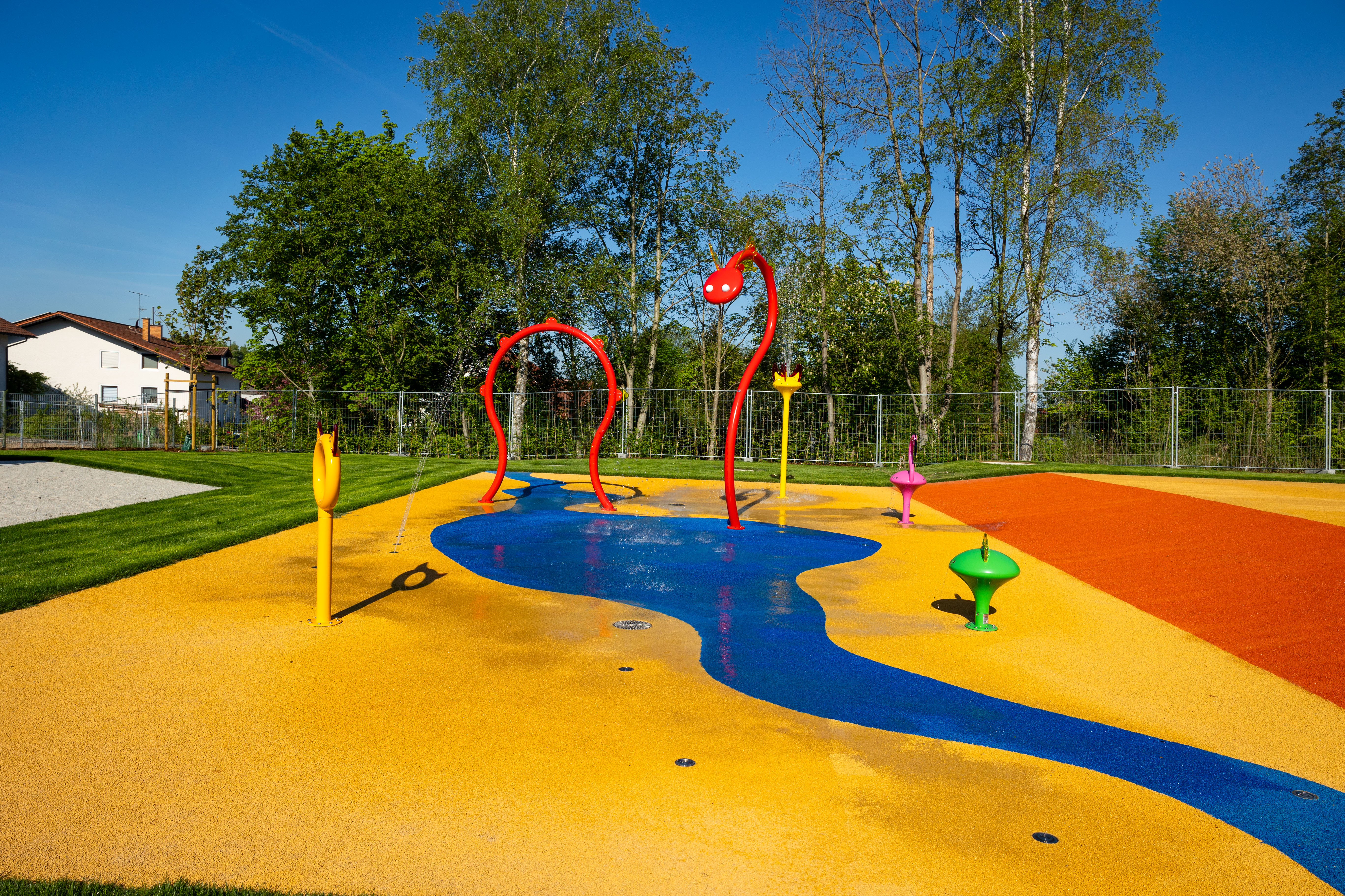 Bunte Wasserspiele und Rasenfläche im Freibad