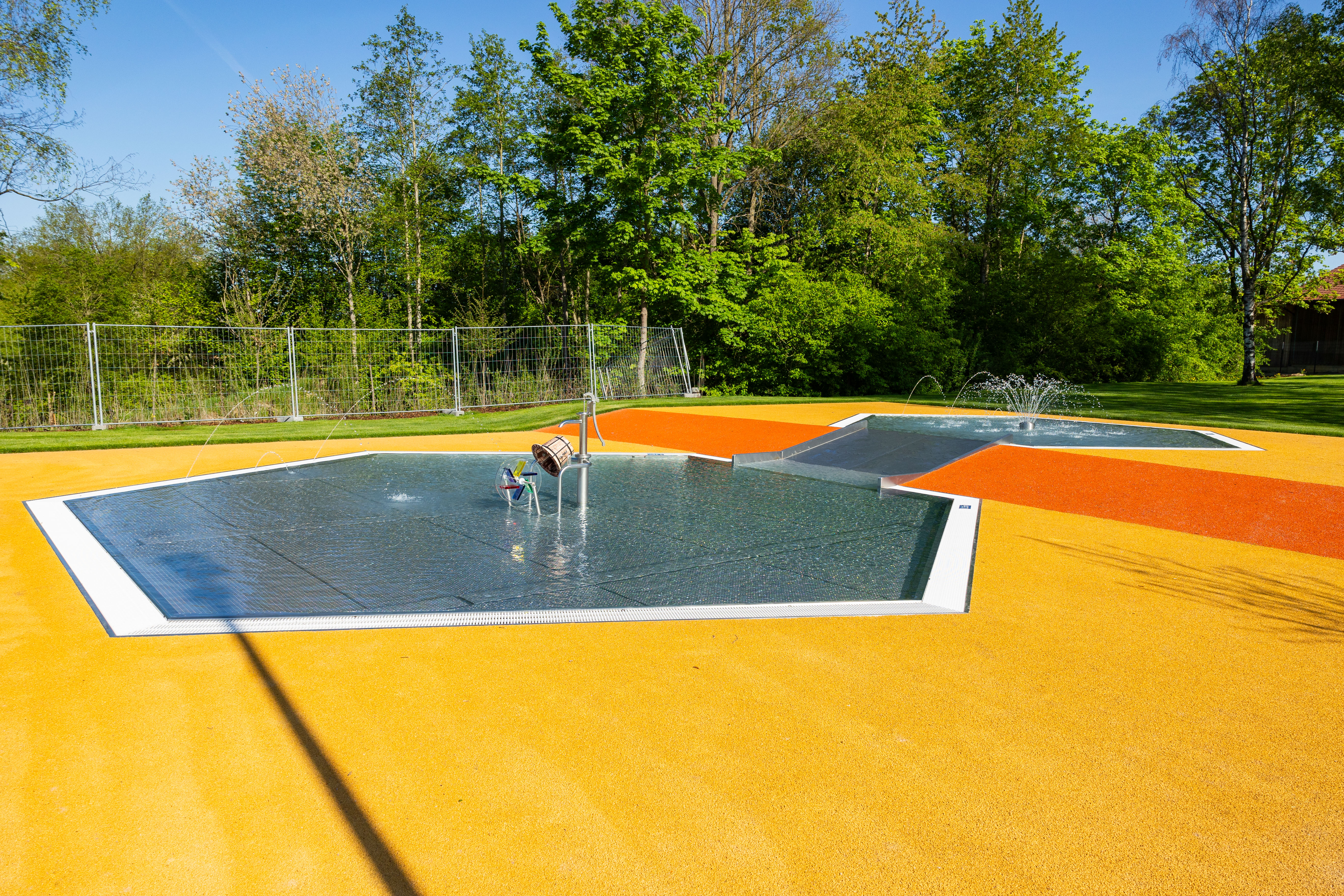 Wasserfontänen spritzen in einem neuen Freibadbereich.