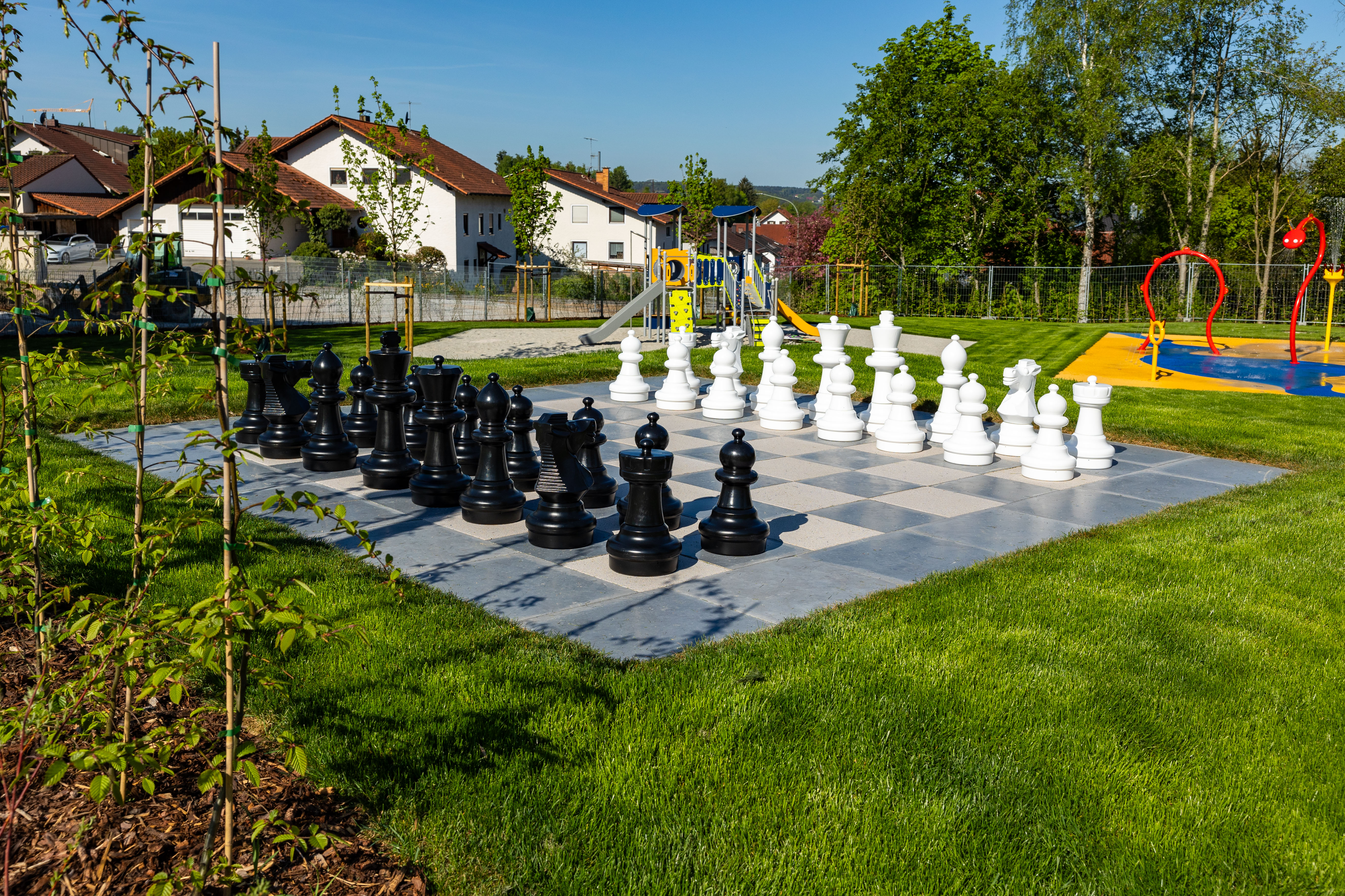 Großes Schachbrett mit schwarzen und weißen Figuren im Freien