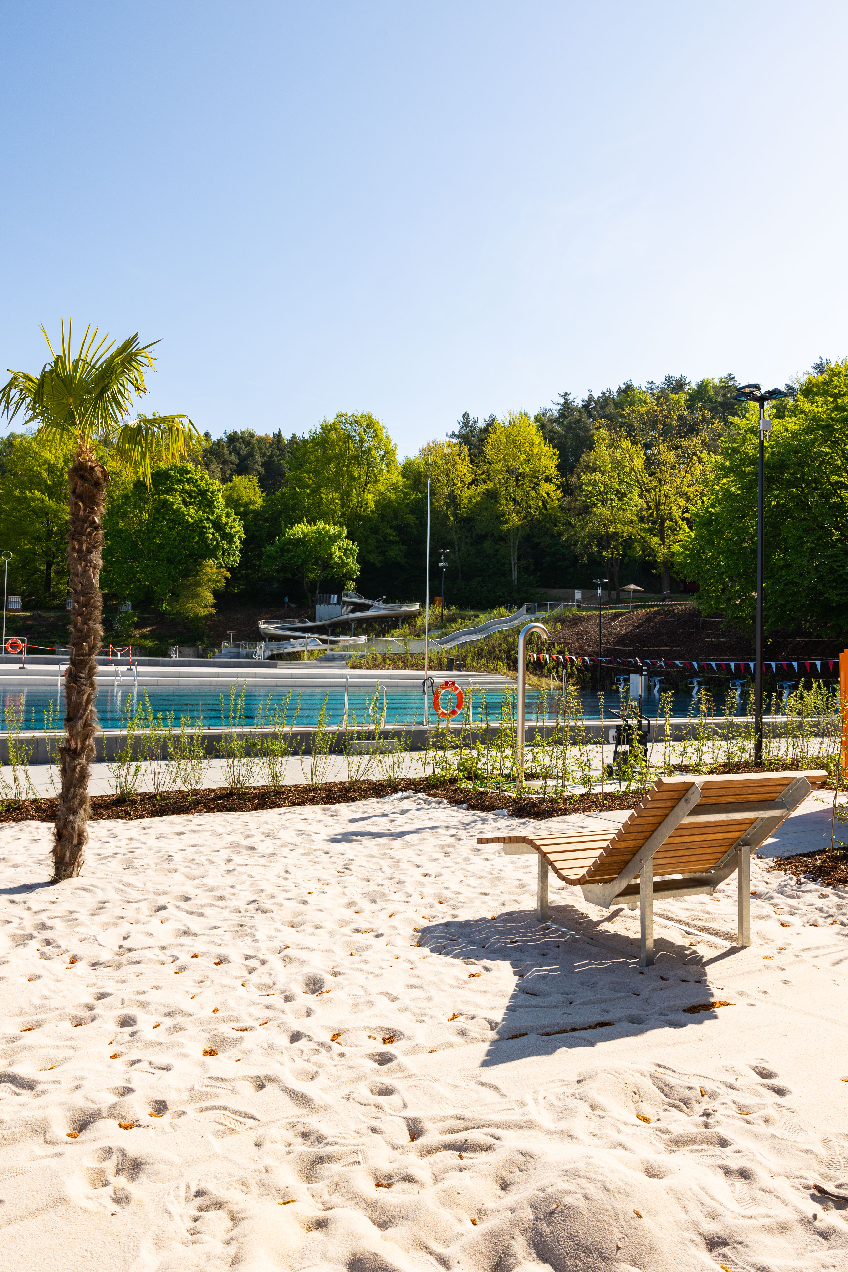 Sonnige Liegefläche mit Sand und Palmen.