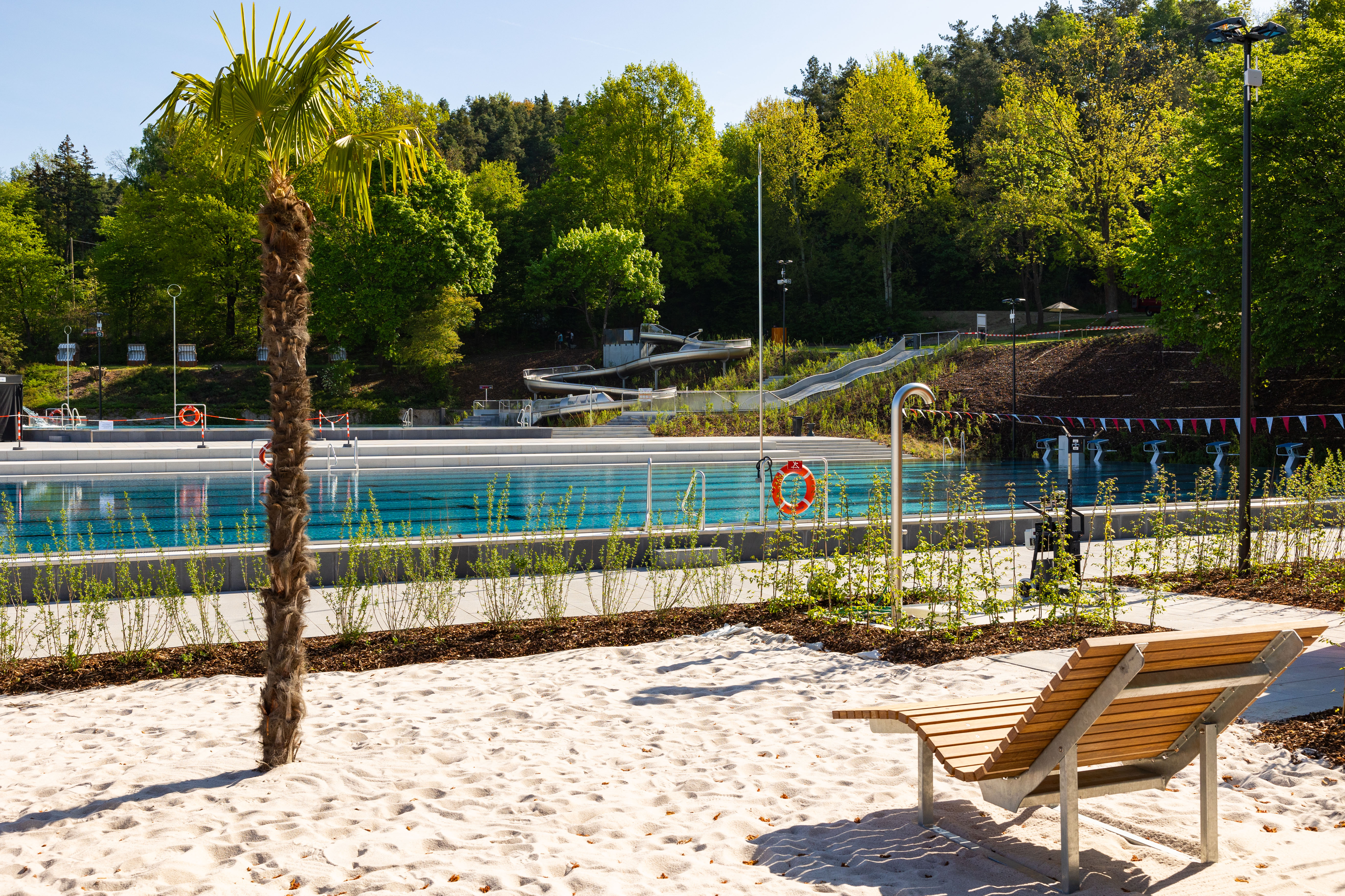 Sicht auf das Freibad mit Palmen und Liegen im Sand