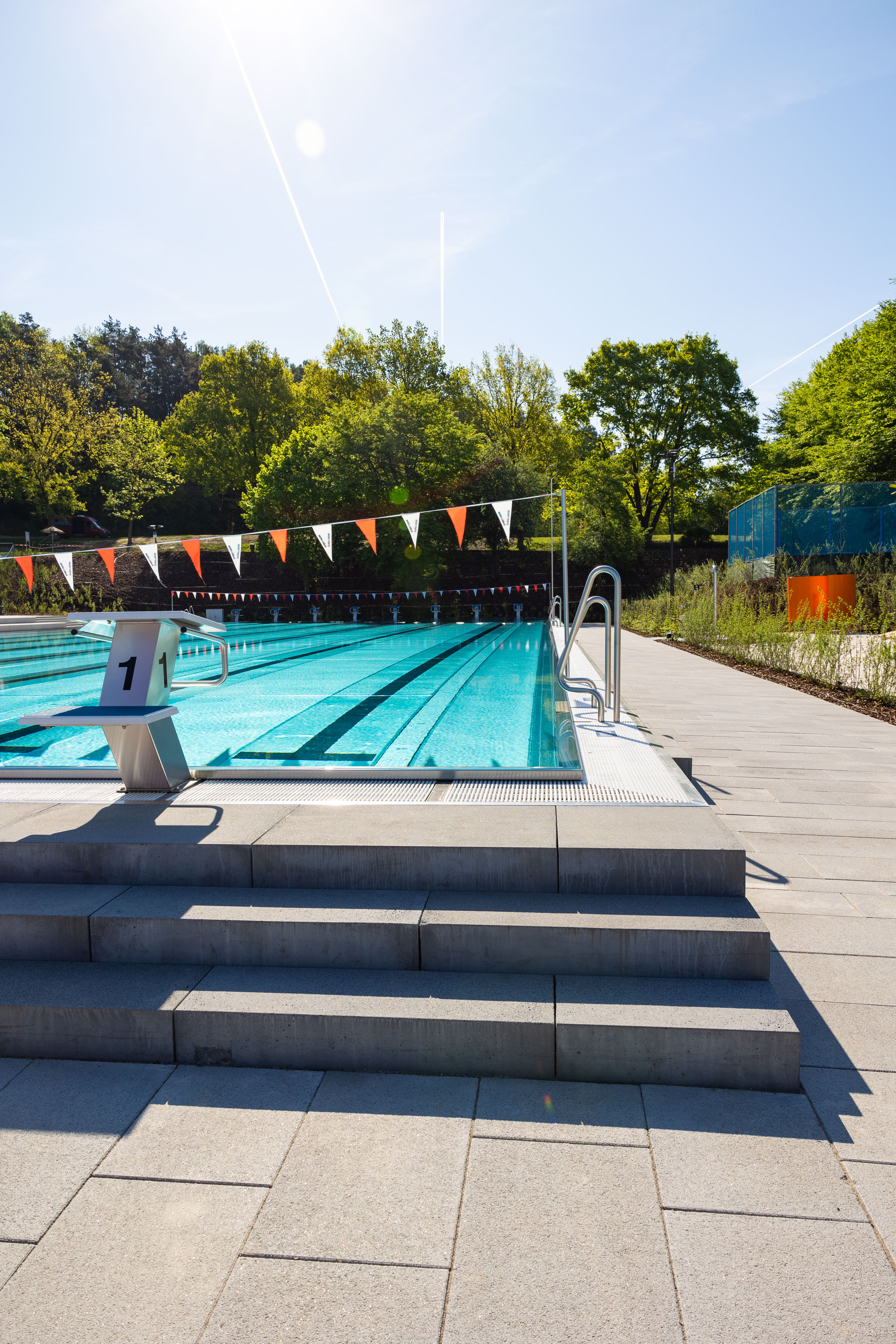 Schwimmbecken mit Startblock und bunten Fahnen.