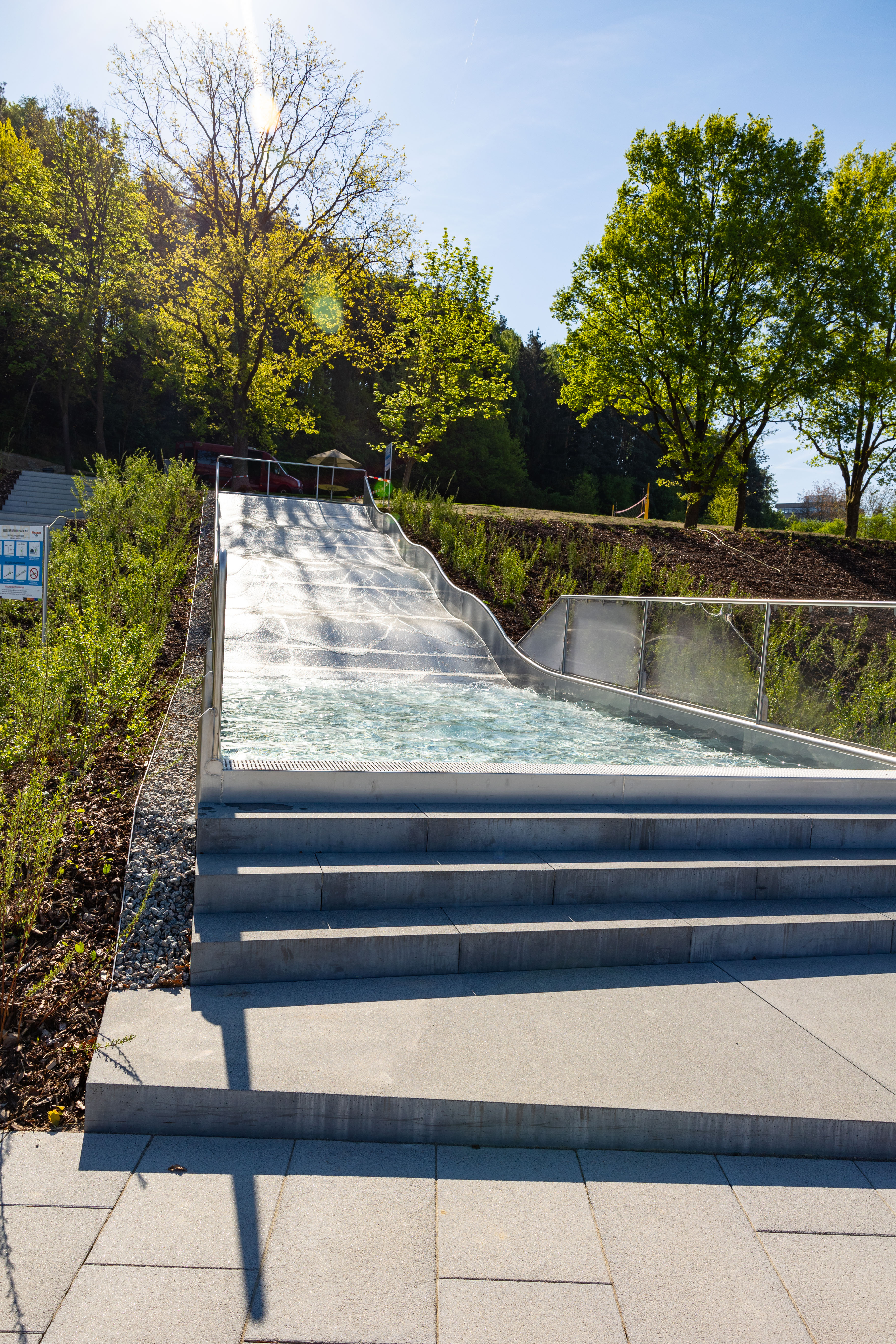 Wasserrutsche mit Stufen und Pflanzen im Hintergrund