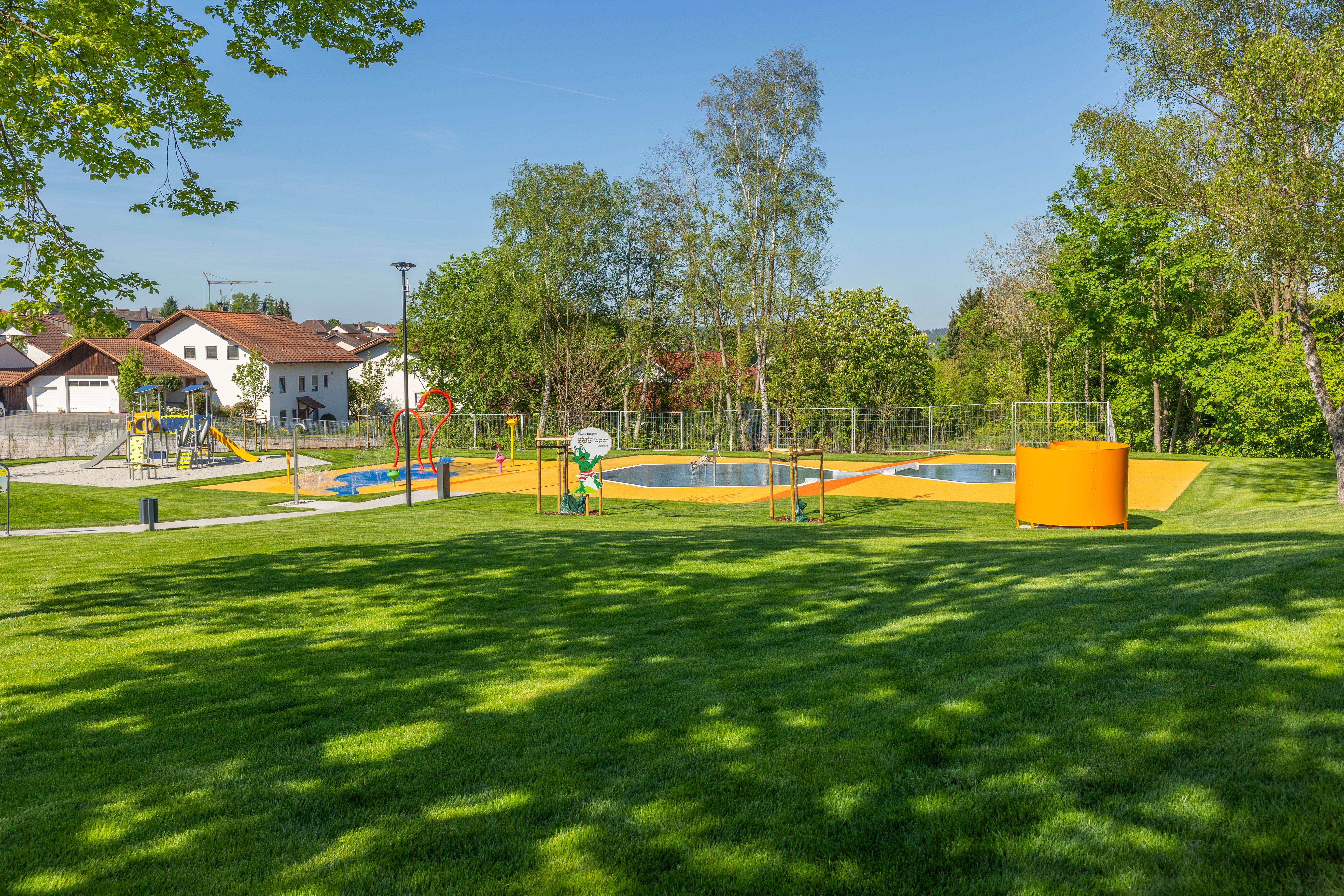 Blick auf das Freibad mit Spielplatz und Rasenfläche.