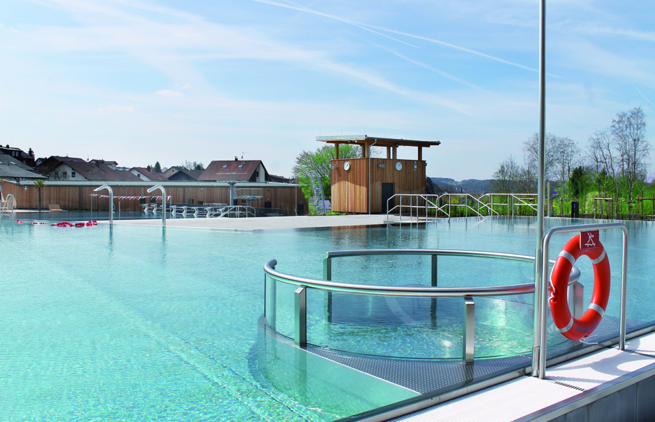 Blick auf das Freibad mit Wasser und Holzgebäude.